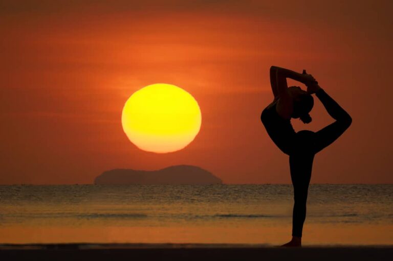 Mujer haciendo yoga frente a una puesta de sol, simbolizando equilibrio en yoga y marketing digital.